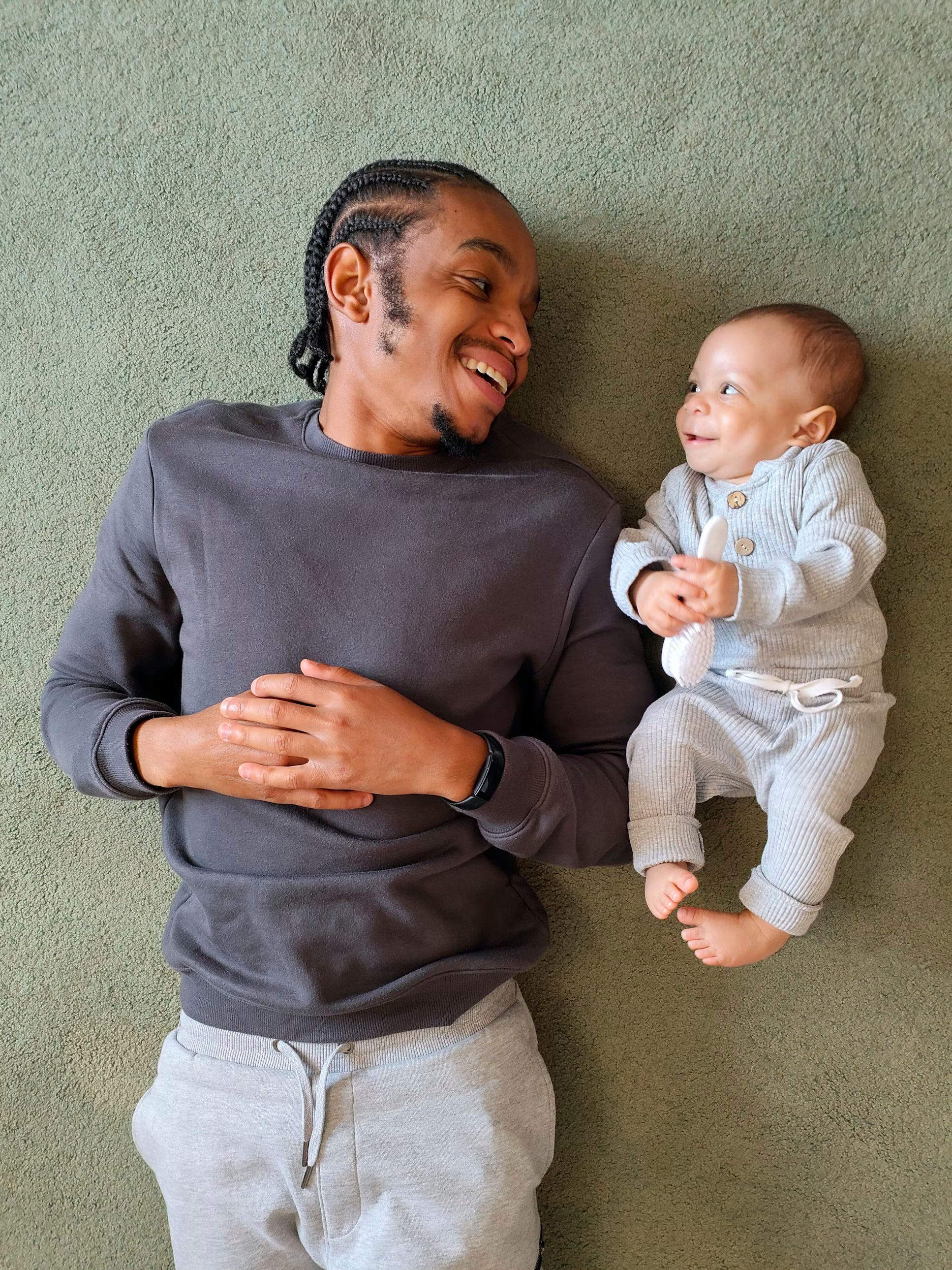A man and baby lying on the floor smiling
