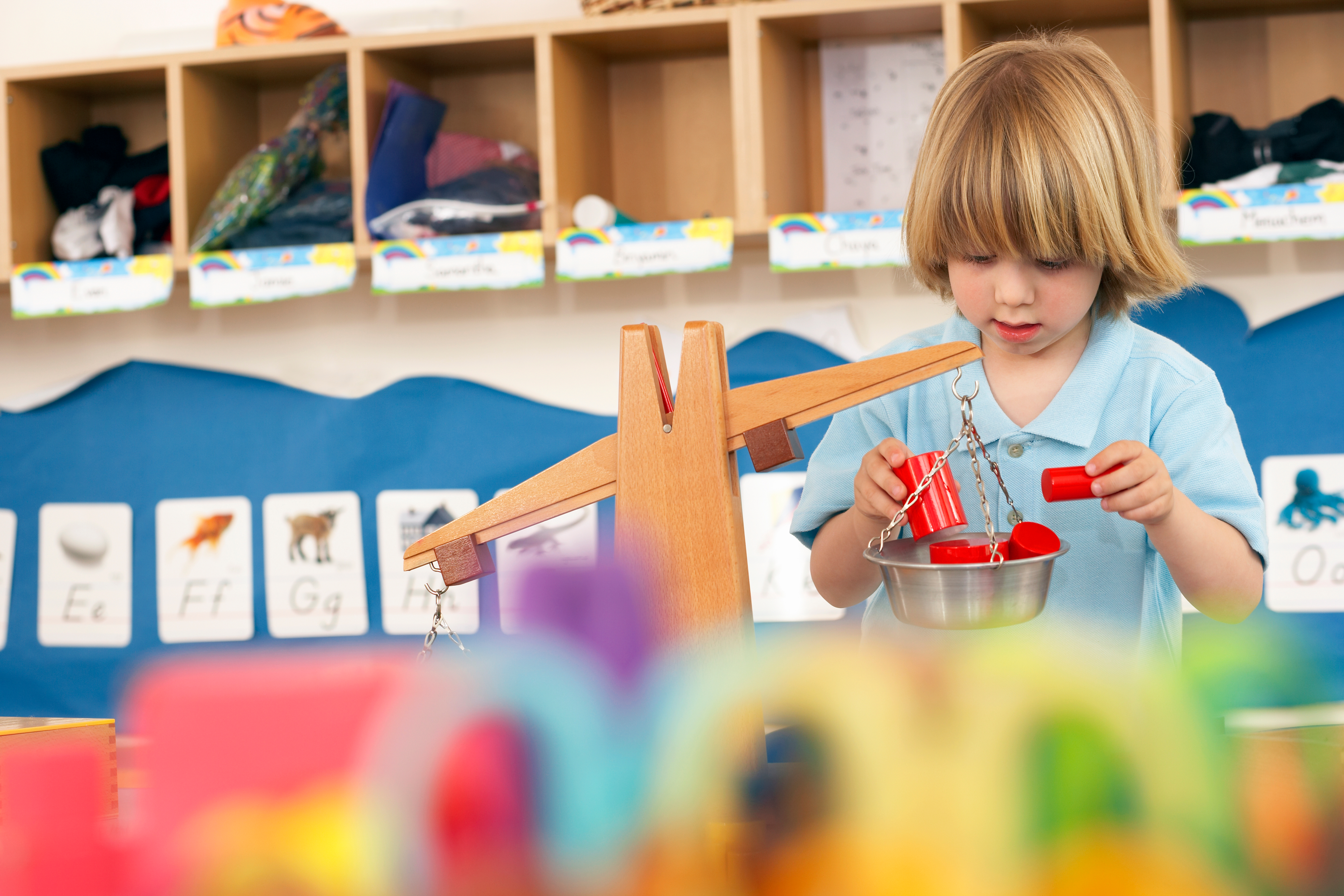 little boy playing with a scale toy in classroom