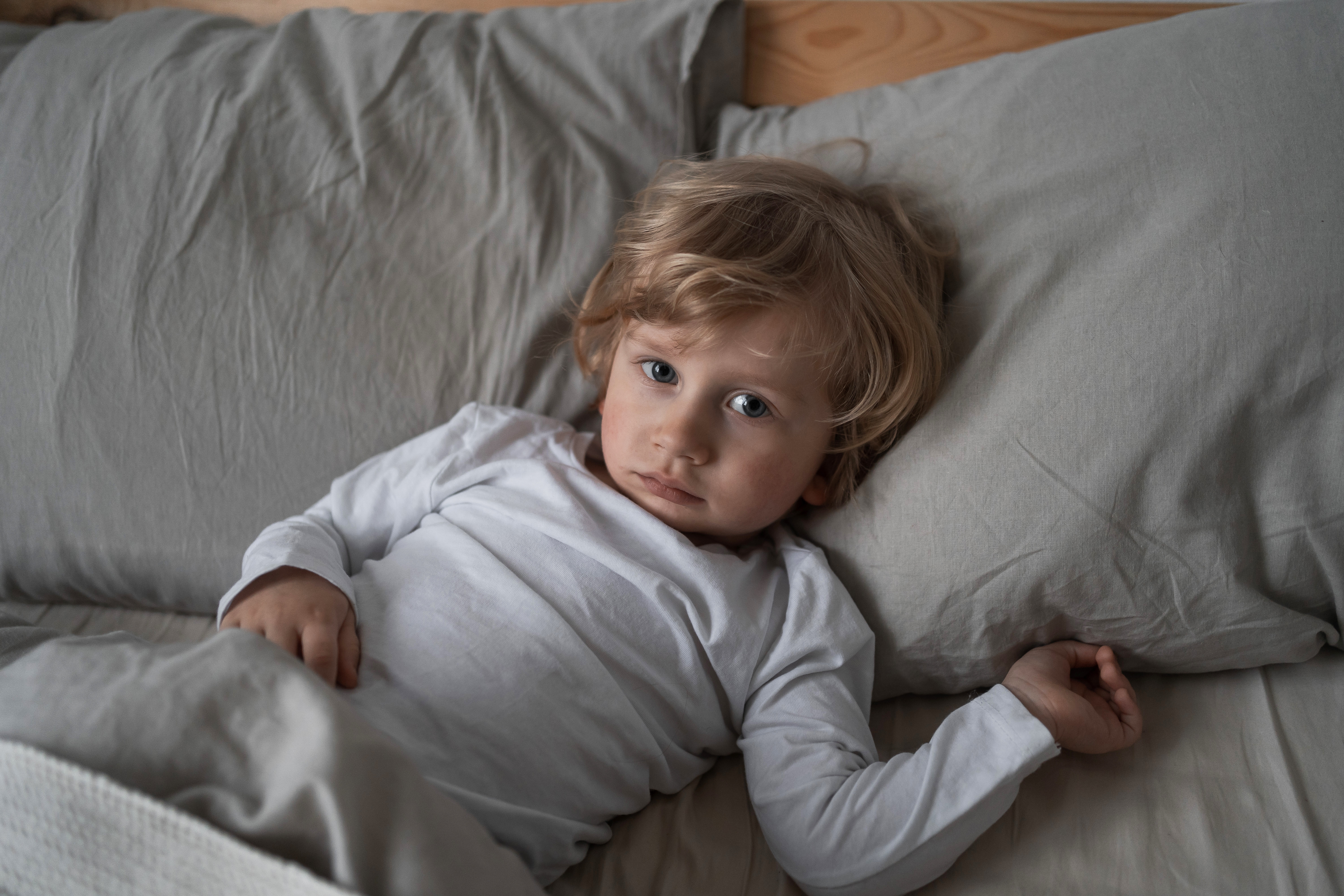 small child in bed with head on pillow