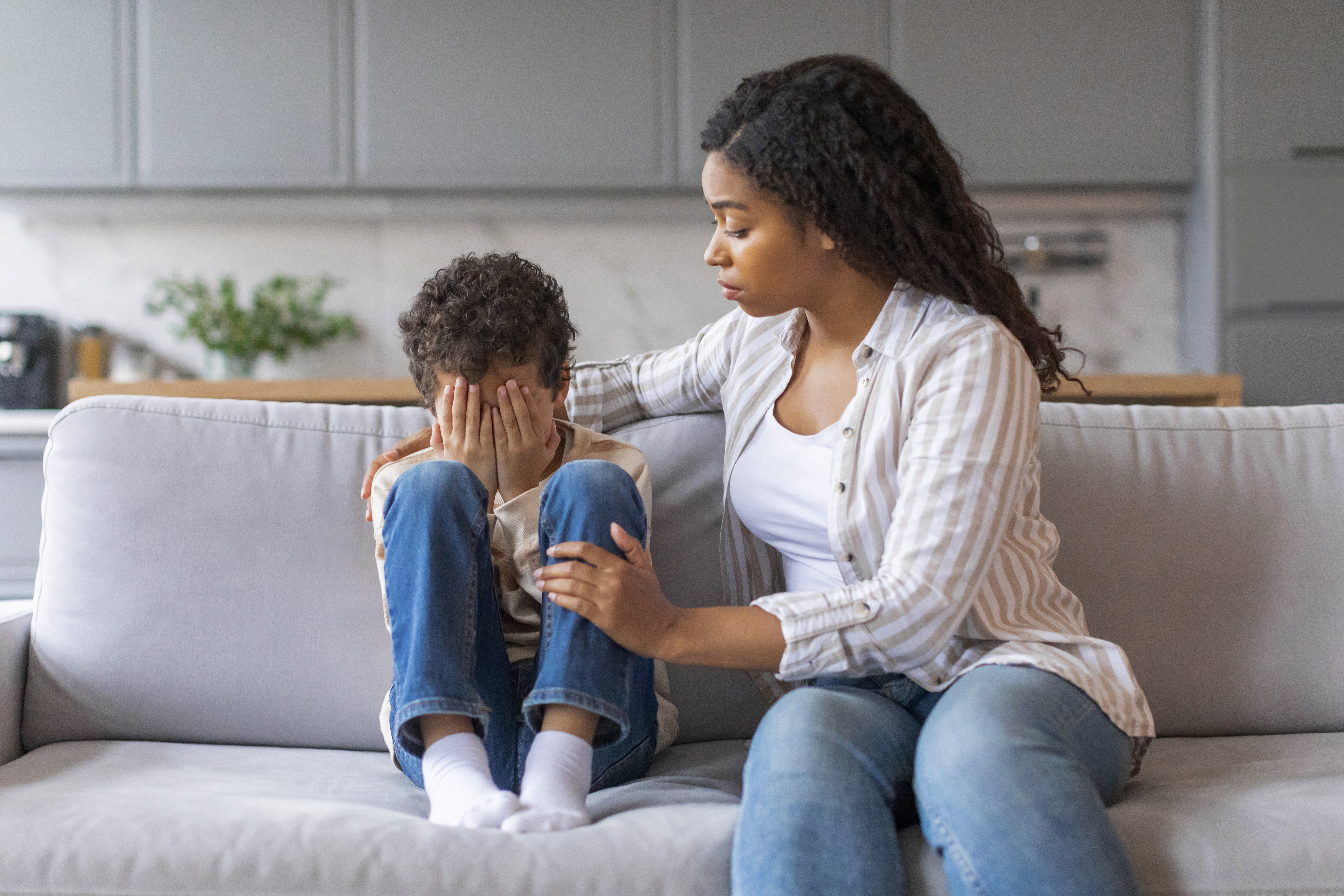 mother sitting on couch, comforting young son