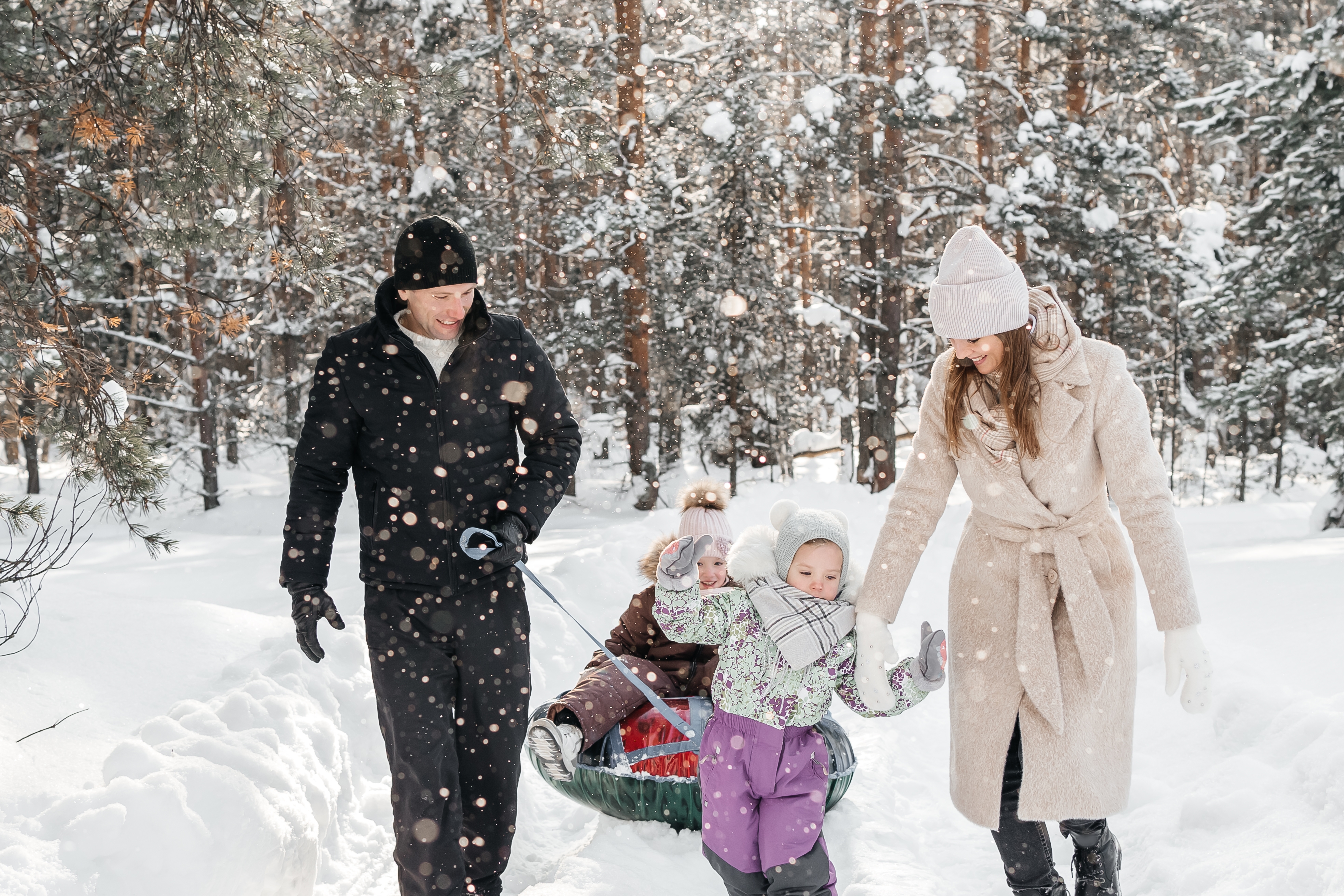 cheerful family taking their kids sledding in the snow