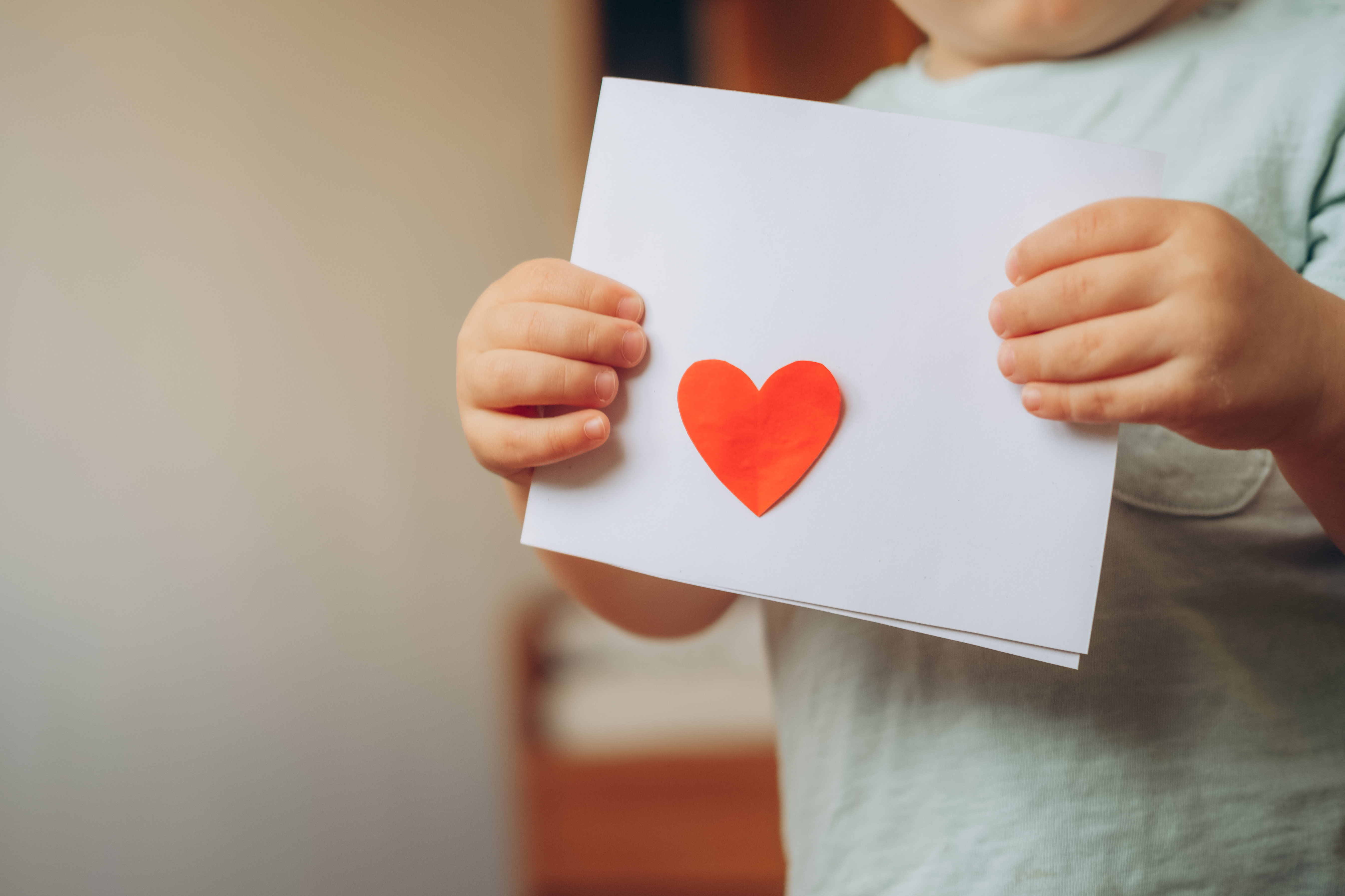 child holding handmade card with a red heart