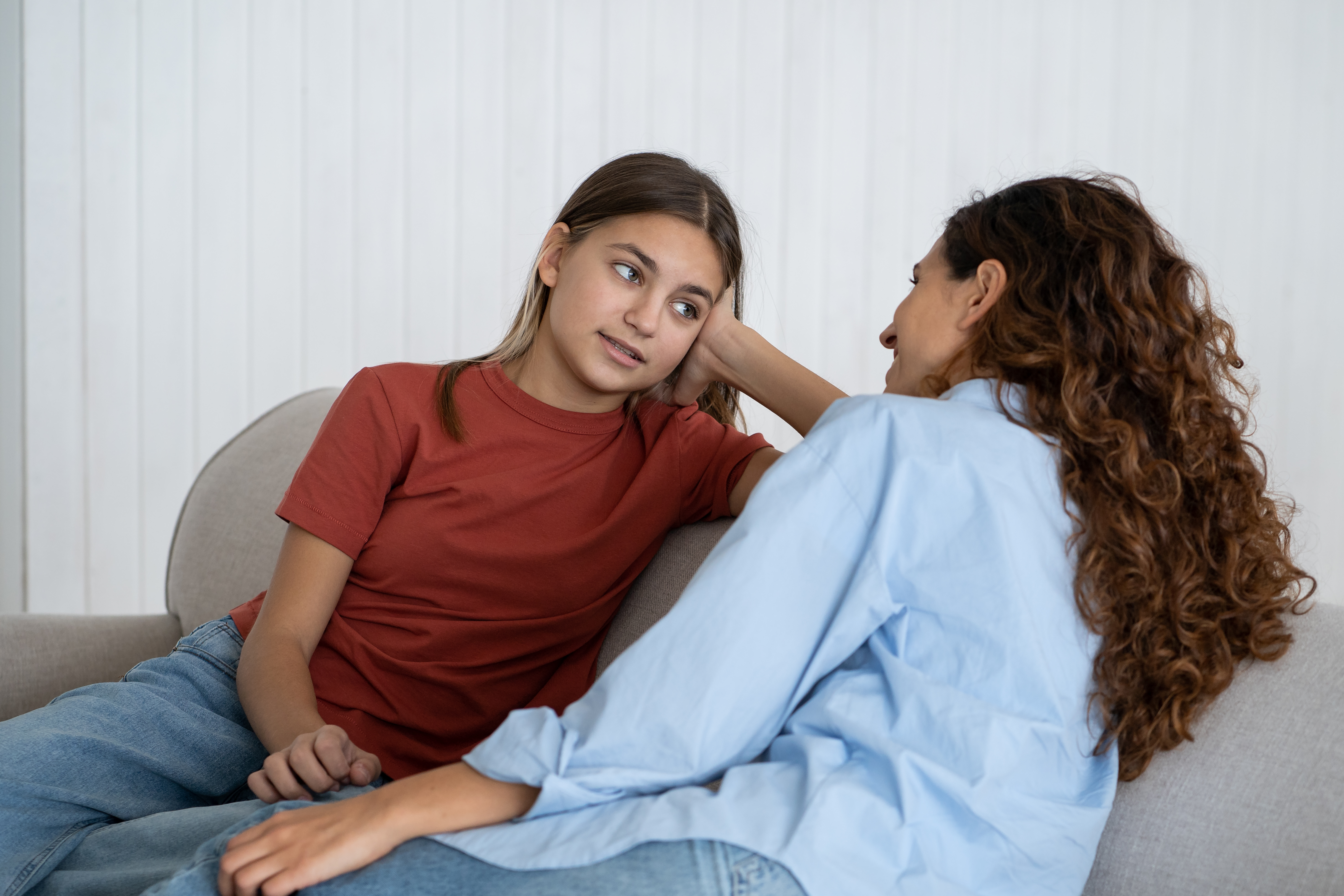 teen girl lounging on couch talking to her mom